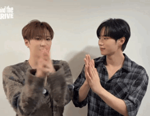 two young men clapping their hands in front of a wall that says mind the rive on it