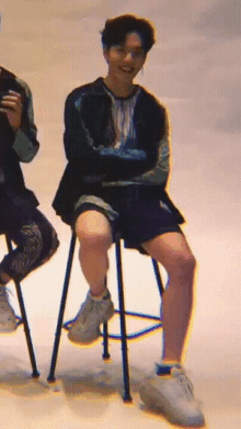 a man sits on a stool with his legs crossed