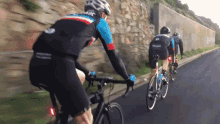 a group of cyclists are riding down a road and one of them is wearing a jersey that says ' cycling '