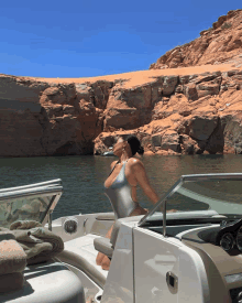 a woman in a swimsuit sits on the back of a boat