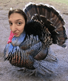 a woman standing next to a turkey with its feathers spread out