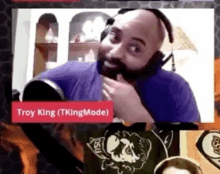 a man with a beard wearing headphones and a sign that says troy king on it .