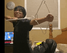 a man in a black shirt is holding a clothes hanger over his head