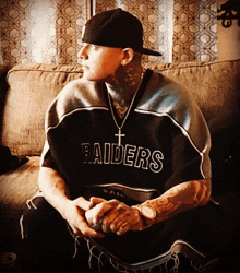 a man sitting on a couch wearing a raiders shirt