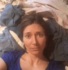 a woman is laying on a bed with a pile of clothes .