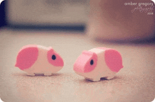 two pink and white guinea pig erasers are sitting next to each other