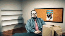 a man sitting in front of a computer with a poster on the wall behind him that says kings of the road