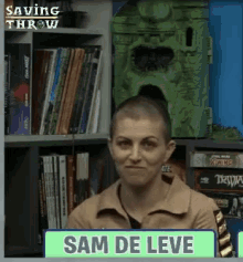 a woman with a shaved head is sitting in front of a shelf with books and a sign that says sam de leve