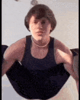 a young man is doing push ups in a black tank top and a necklace .