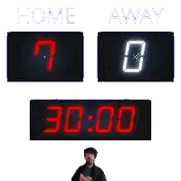 a man stands in front of a scoreboard with home and away written on it