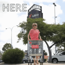 a woman pushing a shopping cart in front of a sign that says galleria