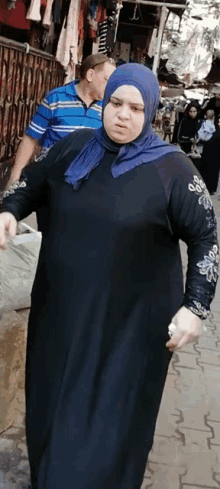 a woman wearing a blue hijab is walking down a street .