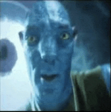 a close up of a man 's face with a blue face and green eyes .