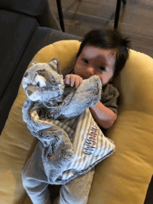 a baby laying on a pillow holding a stuffed animal with the word ginny on it