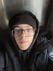 a young man wearing glasses and a beanie