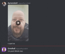 a screenshot of a video of a bald man with a beard and a play button