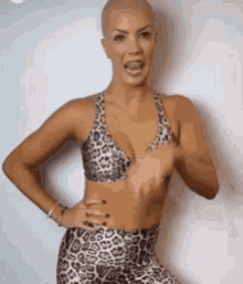 a woman wearing a leopard print bra and leopard print pants is standing in front of a white wall .