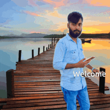 a man is standing on a wooden dock with the word welcome written below him