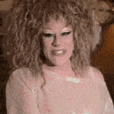 a close up of a woman with curly hair wearing a white top