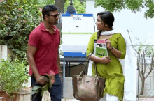 a man in a red shirt and a woman in a green dress are standing next to each other in front of a koel machine