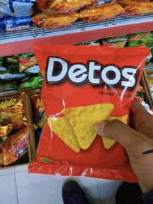 someone is holding a bag of detos chicken wings chips