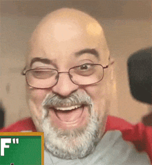 a bald man with glasses and a beard is smiling in front of a green board that says f "