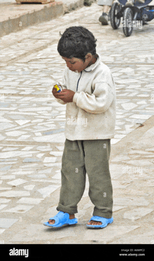 a young boy wearing blue sandals is playing with a toy on a sidewalk