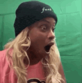 a woman wearing a beanie and a pink shirt is making a funny face .
