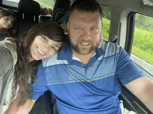 a man and woman are posing for a picture in the back seat of a vehicle