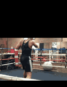 a man in a black tank top is standing in a boxing ring in front of an everlast punching bag