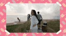 a woman in a white dress is standing on a beach in front of a pink background with syringes and pills