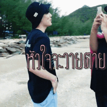 a man is taking a picture of another man on the beach with a phone in his hand