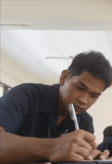 a man sitting at a desk with a pen in his mouth and a shirt that says ' sydney university '