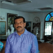 a man with a mustache wearing a purple shirt