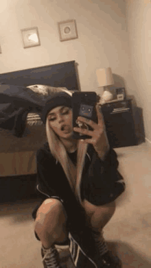 a girl is taking a selfie in a bedroom with her tongue out .