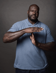 a man wearing a blue shirt is making a stop sign with his hands