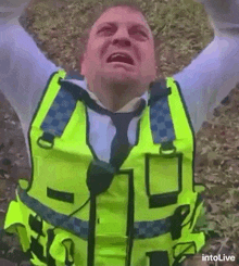 a man in a yellow vest and tie is crying with his arms in the air .