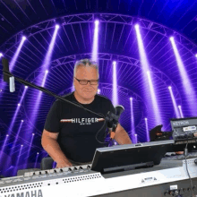 a man wearing a hilfiger shirt playing a keyboard