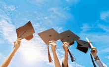 a group of graduates are throwing their graduation caps and diplomas in the air .