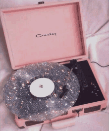 a pink crosley record player with a rhinestone record