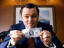 a man in a suit and tie is holding up a dollar bill