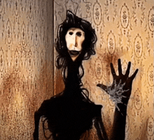 a puppet with a long neck is standing in front of a wall with a pattern