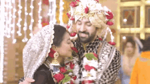 a bride and groom are kissing on their wedding day . the bride is wearing a garland of flowers .