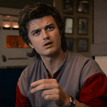a man with a mullet is wearing a grey shirt and a red shirt
