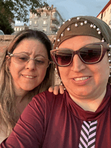 two women posing for a picture one wearing glasses and the other wearing sunglasses