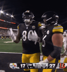 two football players are standing on a field with a scoreboard behind them that says tnf 2nd & goal