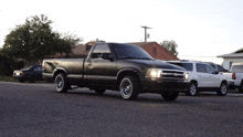 a black truck with white tires is parked on the street