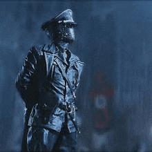 a statue of a man in a military uniform is standing in the rain in the dark .