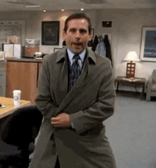 a man wearing a trench coat and tie is standing in a room .
