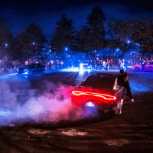 a dodge charger is doing a burnout in front of a crowd at night